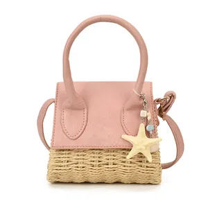 Pink faux leather and straw woven crossbody bag with starfish pendant on white background