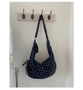 Detail of navy blue polka dot shoulder bag with bow drawstring and canvas strap