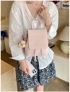 Detail of pink faux leather mini backpack with drawstring closure and cute teddy bear charm
