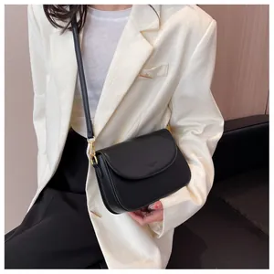 Detail of minimalist black crossbody bag with embossed logo and golden hardware