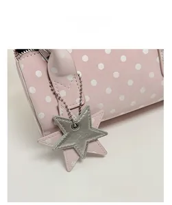 Detail of pink polka dot handbag featuring a silver star-shaped metallic leather charm