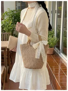Detail of handwoven straw tote bag with a white lace bow and round dual handles