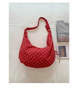 Detail of red polka dot canvas bag showing wide adjustable strap and zipper detail