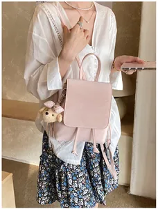 Detail of light pink PU leather backpack with drawstring closure and plush dog charm