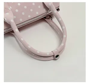 Close-up of pink polka dot bowling bag featuring padded handles and silver metal hardware