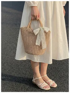 Detail of hand-woven tote bag featuring a white lace bow and semi-circular woven handle