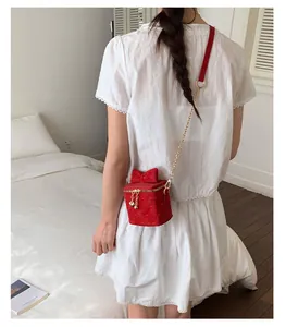 Vue détaillée du mini sac rouge matelassé avec breloque cœur sur une robe blanche