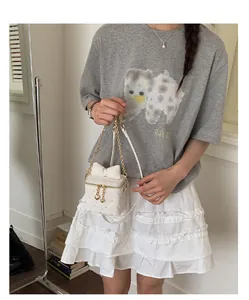 Détail d'un sac à main blanc matelassé avec un grand nœud et une chaîne dorée