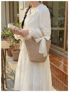 Close-up of straw woven tote bag featuring a white lace bow detail and fine texture