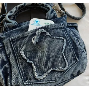 Detailed close-up of a blue denim tote bag featuring a star-shaped stitched front pocket
