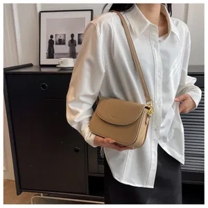 Detailed view of khaki crossbody bag with gold hardware worn with white shirt