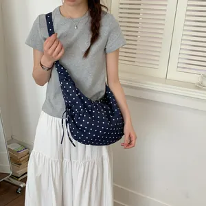 Navy blue polka dot shoulder bag with drawstring detail in a crescent moon shape