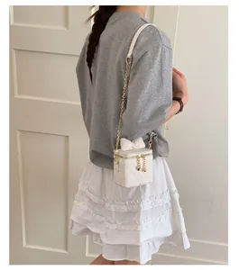 Gros plan d'un mini sac matelassé blanc avec nœud 3D et bandoulière chaîne dorée