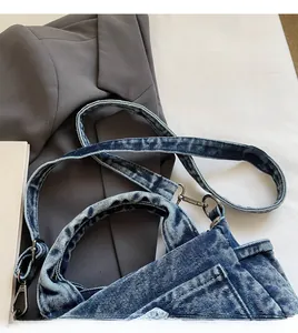 Detail view of denim crossbody bag showing adjustable long strap and silver metal hooks