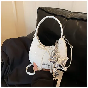Detail van witte halve maan tas met zilveren sterpatronen en een strik als versiering