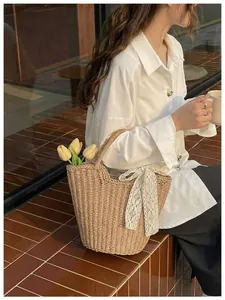Close-up of woven straw tote bag featuring white lace bow and decorative tulips