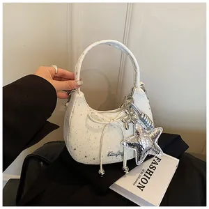 Detail van een witte schoudertas met strik, zilveren sterpatronen en een sterrenhanger