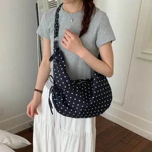 Navy blue polka dot crescent shoulder bag with side knot detail and zipper closure