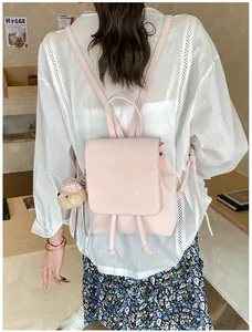 Detail of pink PU leather backpack with a drawstring closure and a plush bear pendant