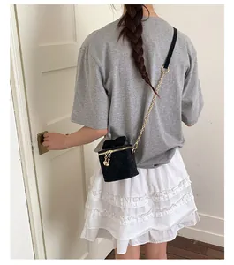 Détail d'un mini sac à chaîne matelassé noir avec un nœud décoratif sur la bandoulière