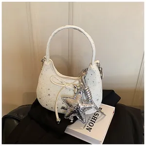 Detail van witte tas met sterrenprint, zilveren sterhanger en strik-accent
