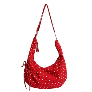 Red polka dot crescent shoulder bag with drawstring bow and tassel pendant