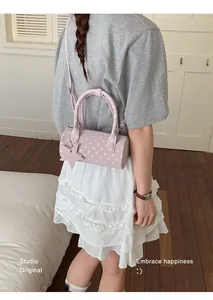 Close-up of pink polka dot barrel bag with star pendant on a female model
