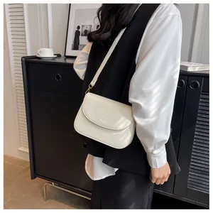 Close-up of a minimalist cream flap crossbody bag with adjustable strap and gold hardware