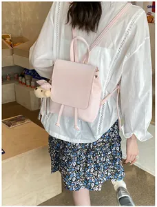 Rear view of a model wearing the light pink backpack with a cute teddy bear charm