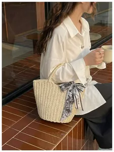 Detail of straw woven tote bag featuring a decorative Paris printed silk scarf handle