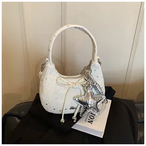 Detail van crème crossbodytas met strik, zilveren sterren en metalen sterhanger