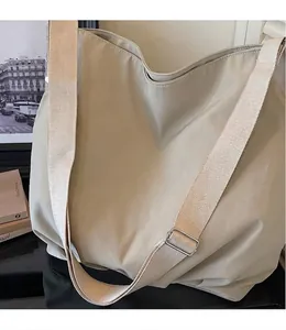 Detail van de beige canvas draagtas met brede verstelbare riem en zilveren metalen gesp