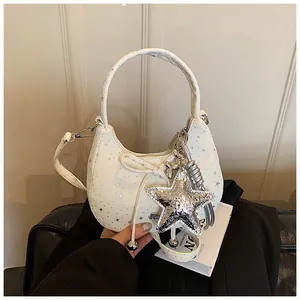 Detail van de crème crossbodytas met zilveren sterren en een ster-vormige hanger