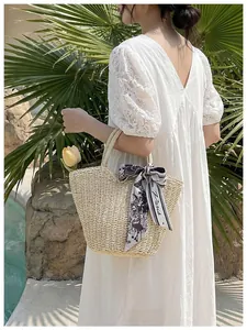 Detail of hand-woven straw tote bag with elegant Paris print silk scarf on handle
