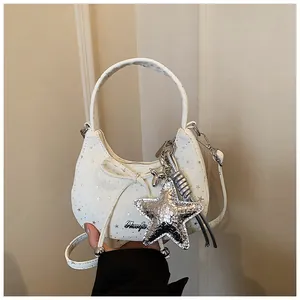 Detail van witte halve maan tas met zilveren sterren, strik en een sterrenhanger