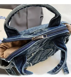 Close-up of smooth silver metal zipper on washed denim bag with raw edge details