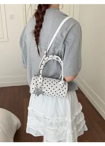 Detailed back view of a white polka dot bowling bag with a silver star pendant