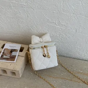 Détail de la texture matelassée en cœur et du nœud sur un mini sac blanc