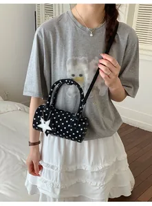 Detailed view of a black polka dot cylinder bag with a white star charm and top handle