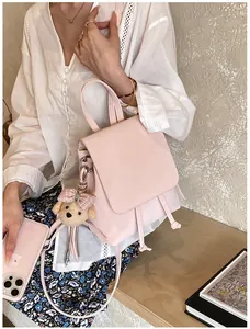 Close-up of light pink mini backpack with cute teddy bear charm and drawstring detail