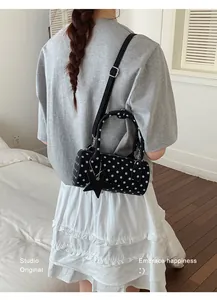 Polka dot cylinder bag in black with star charm and adjustable strap on a model