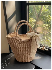 Close-up of woven straw tote bag featuring white lace bow and natural shadow detail