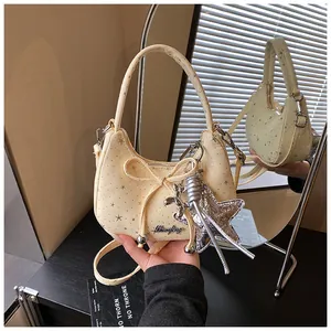 Detail van beige maanvormige tas met sterrenprint, strik en zilveren hondenbedels