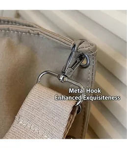 Detail van de zilveren metalen haak en geweven schouderband op een beige grote tas