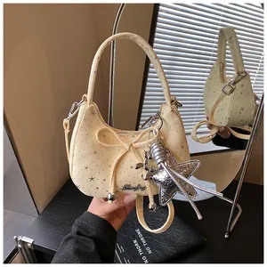 Detailweergave van beige crossbodytas met sterborduursel en metalen sterrenhanger