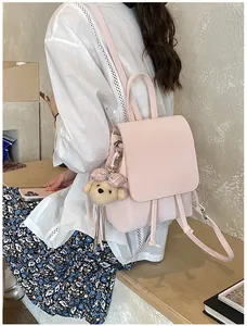 Detailed back view of a pink pebbled leather backpack with cute puppy plush charm