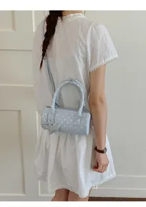 Detail of light blue polka dot cylinder bag with star pendant and soft faux leather texture
