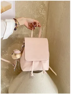 Detail of light pink leather backpack with a plush bear charm and drawstring closure