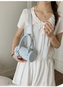 Light blue polka dot cylinder bag detail with a silver star pendant and slim strap