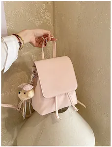 Close-up of light pink PU leather mini backpack with cute teddy bear charm detail